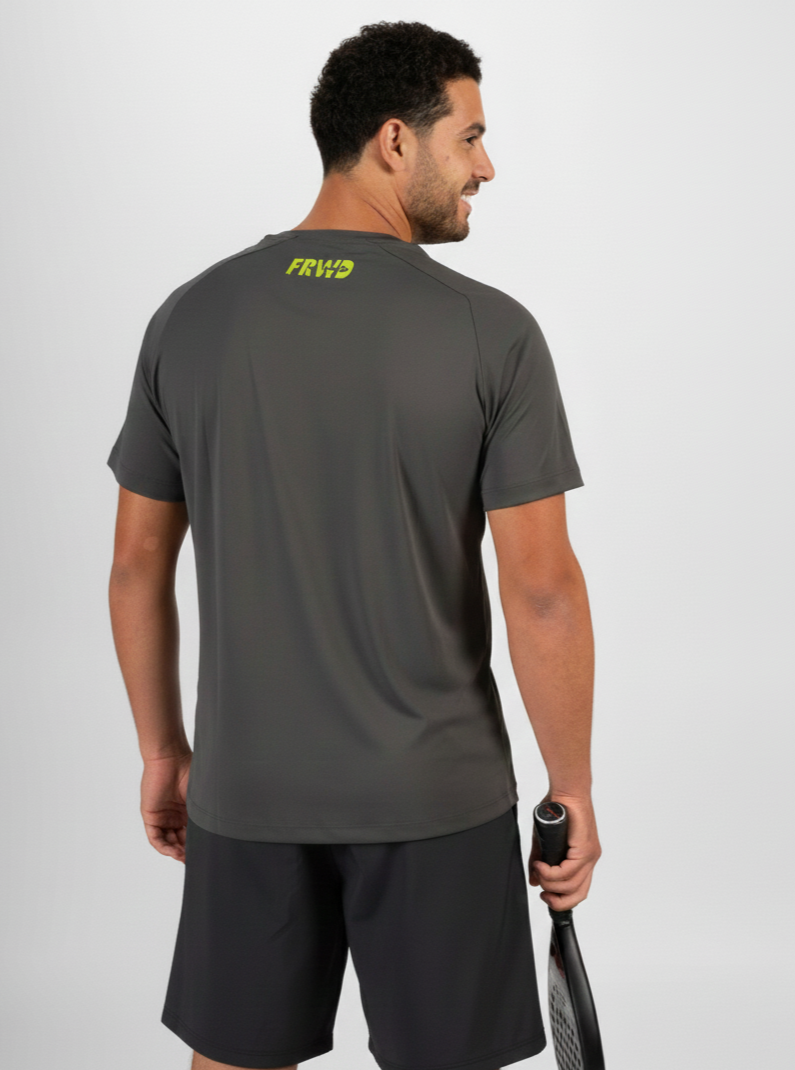 Man wearing a gray t-shirt with a logo on the back, holding a tennis racket, against a white background